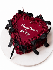 Beyaz fonda bordo kalp şeklinde siyah fiyonklu Sagittarius Baby mesajlı pasta