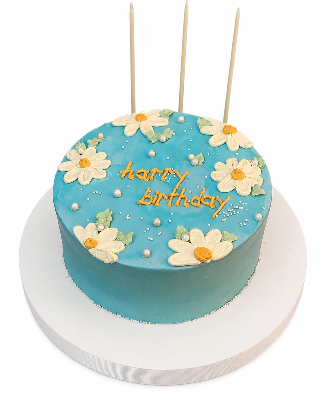 Beyaz arka planda mavi papatyalı Happy Birthday mesajlı pasta